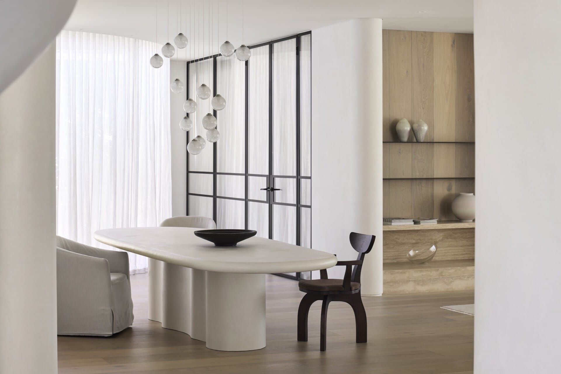 Minimalist dining area featuring engineered timber flooring, curved architectural lines