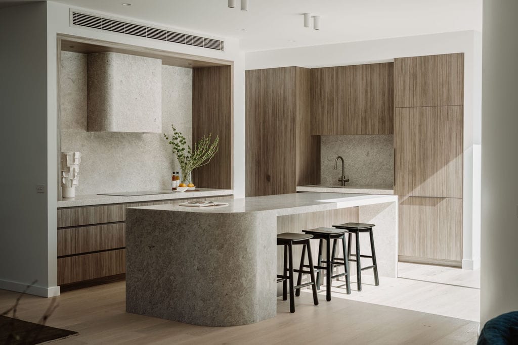 Kitchen at Perth Street in Prahran, with a stone island, timber joinery and Alta timber flooring