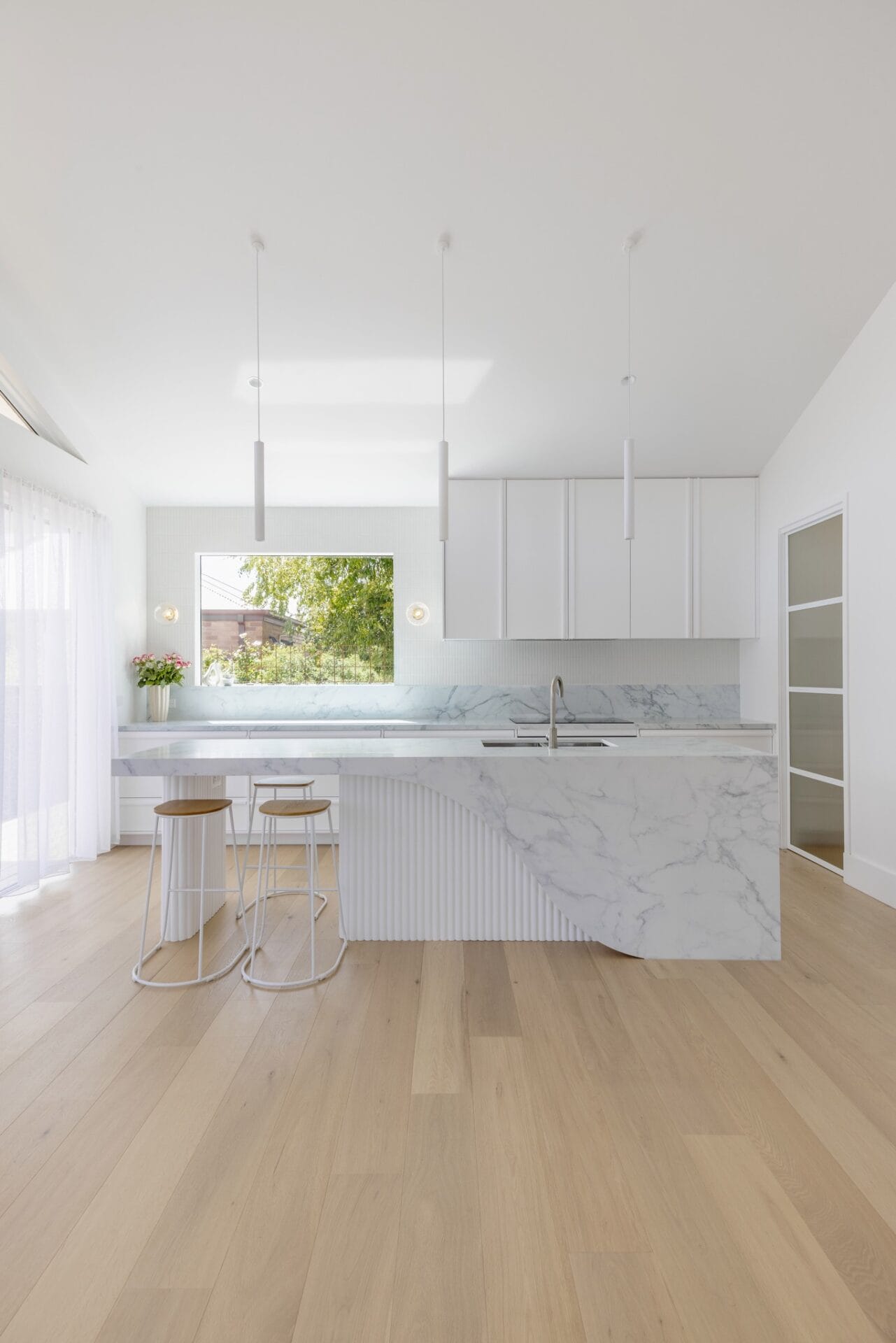 All-white kitchen at Costa in Benalla, with a marble island, garden window and Calypso timber flooring