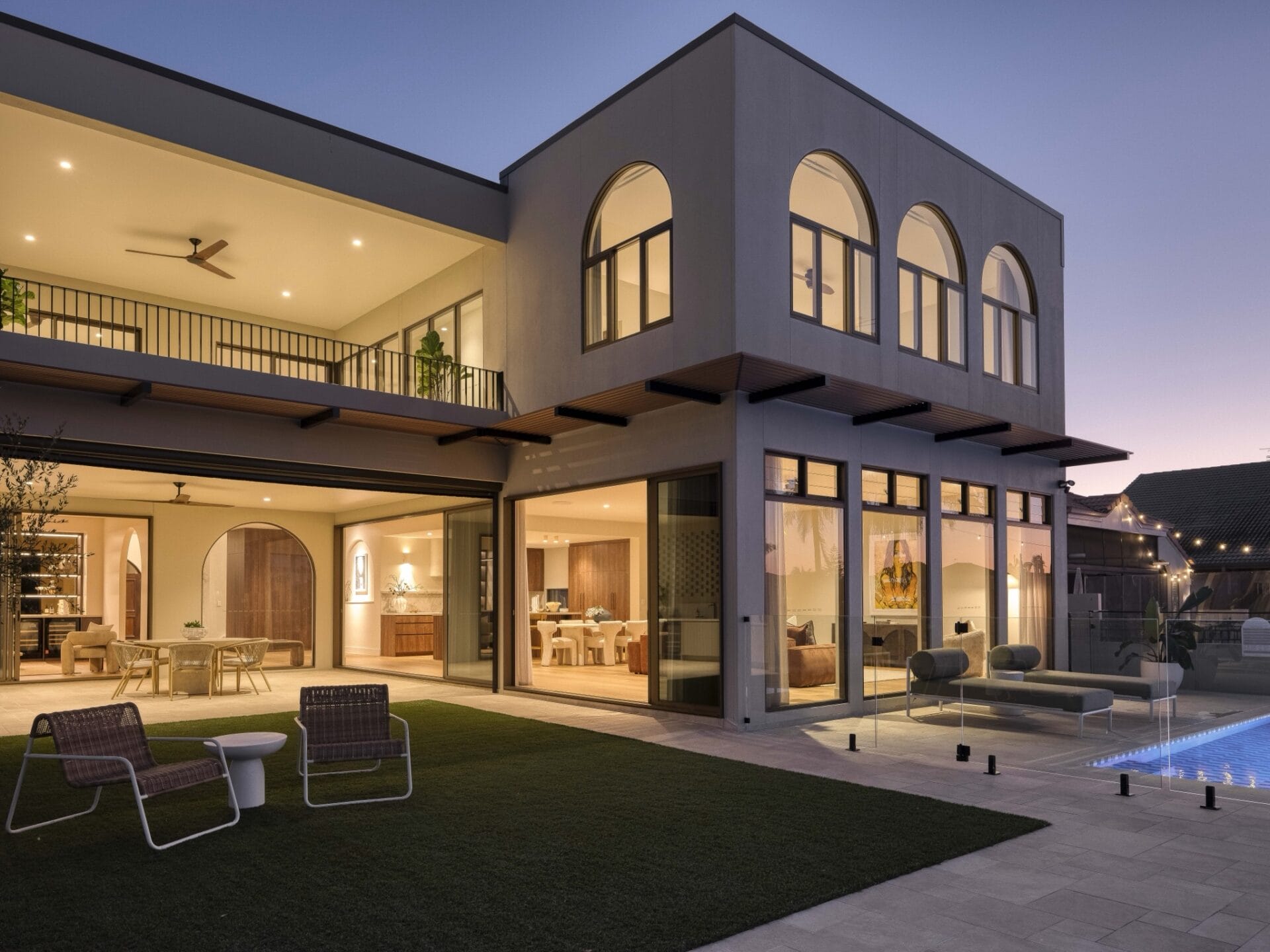 Twilight view of MARÈA's arched rear façade, pool, and alfresco zone in Mermaid Waters