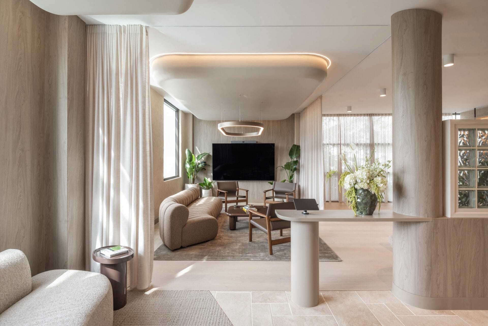Curved ceiling and ring pendant above a sofa and screen in the Brisbane business lounge