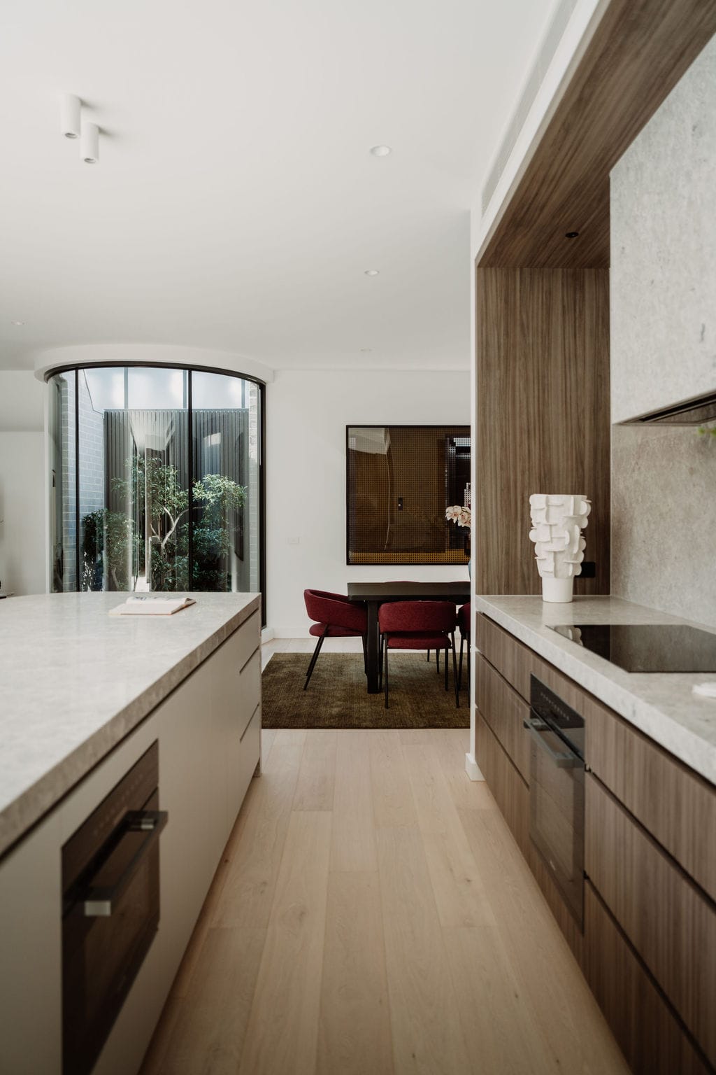 Curved glazing and white render at the sculptural staircase, lit from above