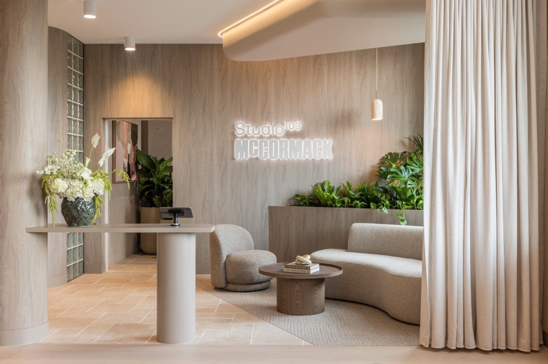 Reception at Studio 103 and McCormack's Brisbane studio, with curved banquette seating, planting and signage