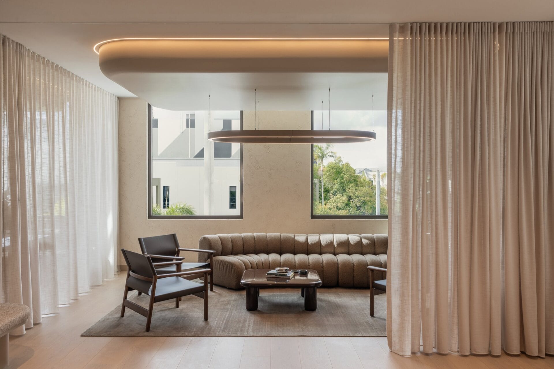 Informal meeting area with timber armchairs, boucle sofa and a low table beside a window