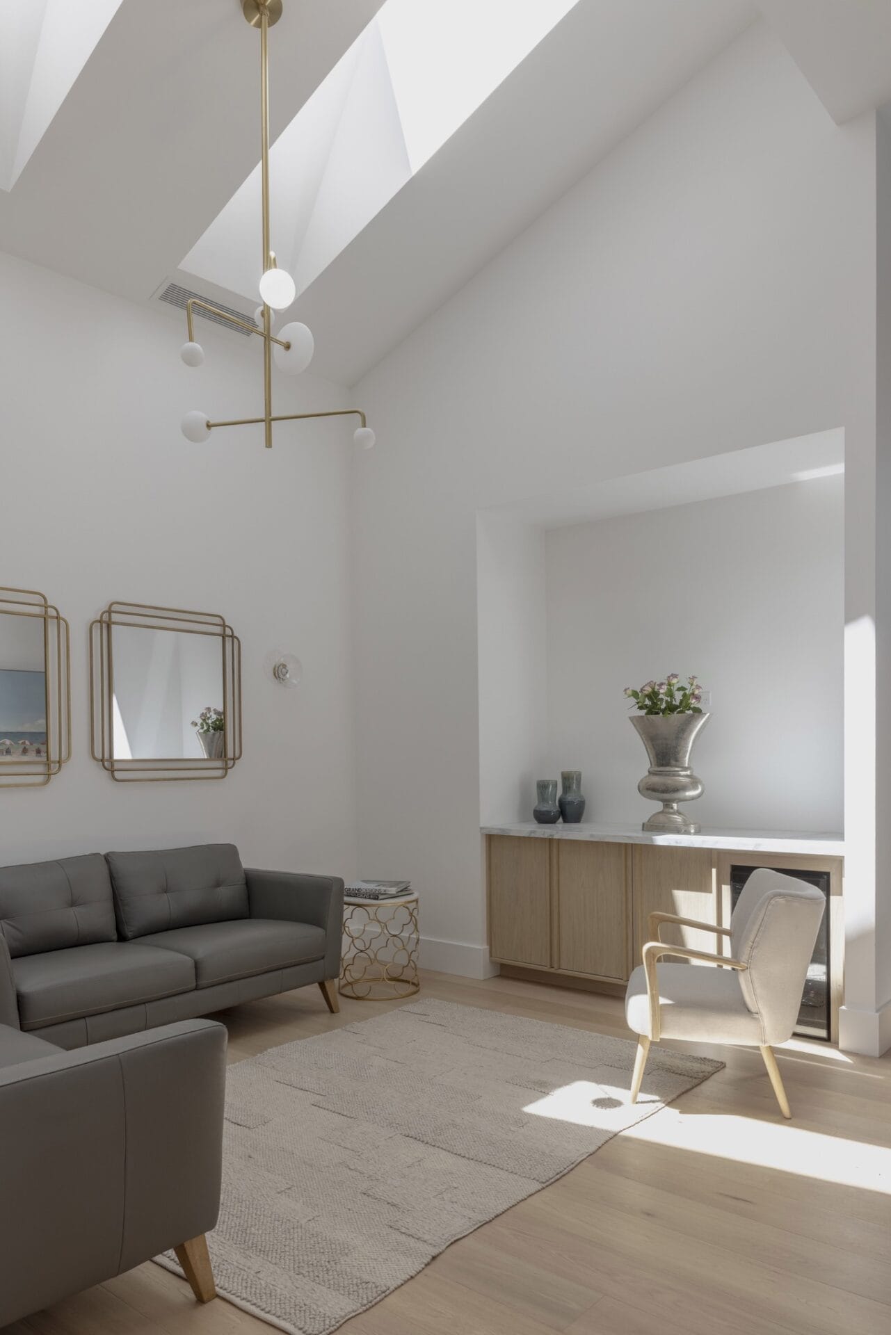 Brass pendant light suspended in a white stairwell void beneath a raked ceiling