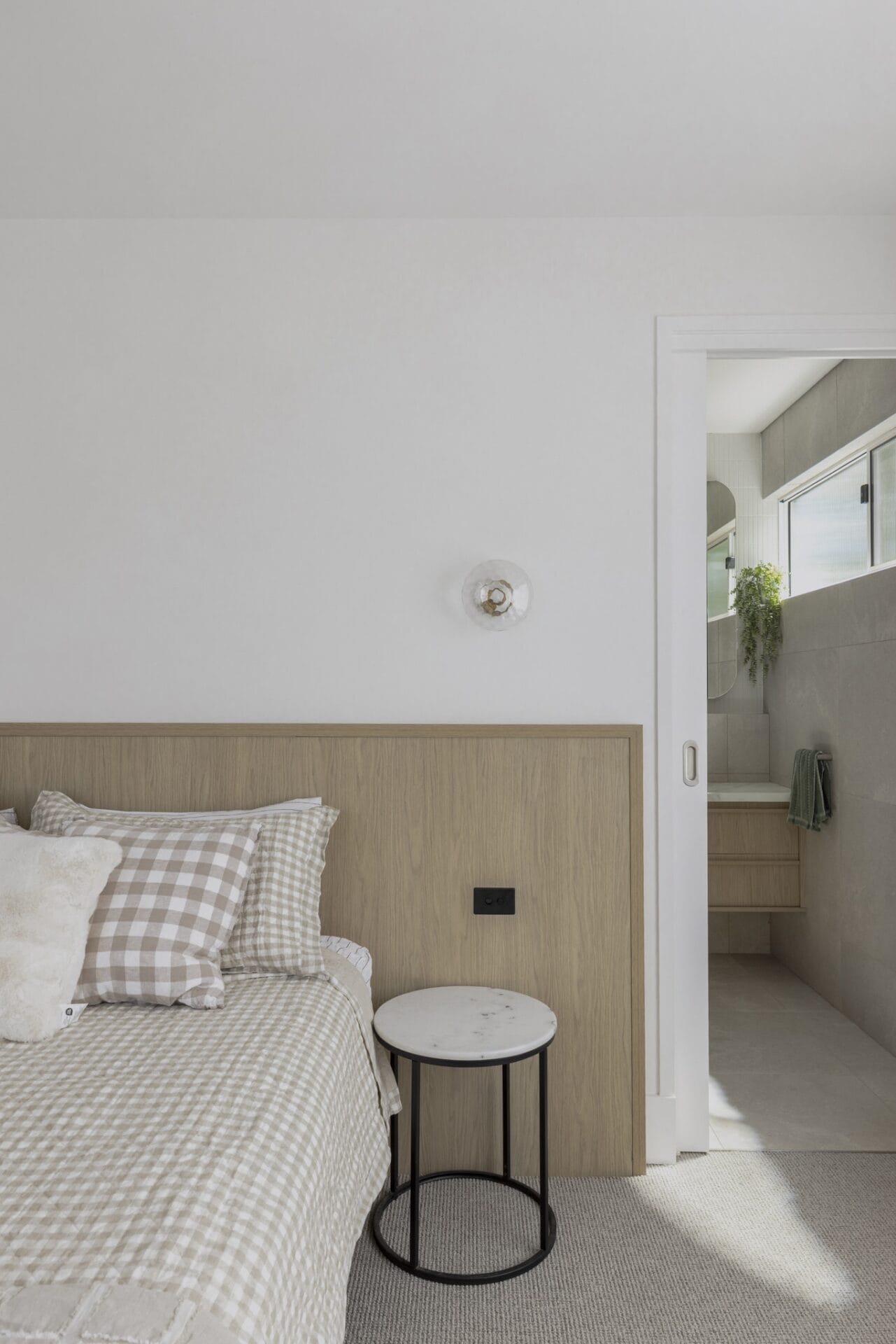 Bedroom with checked bedding and a slim bedside table over timber flooring
