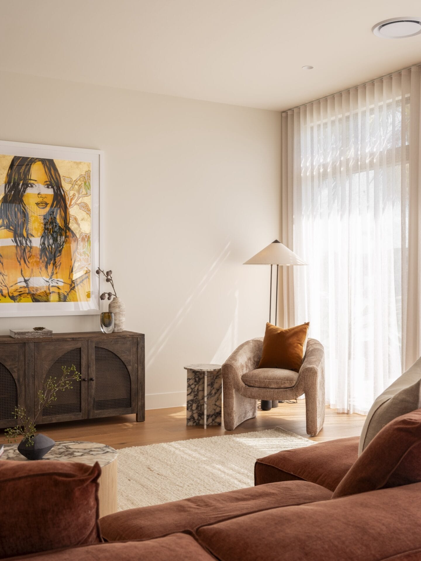 Lounge at MARÈA with rust sofa, timber sideboard and framed portrait artwork
