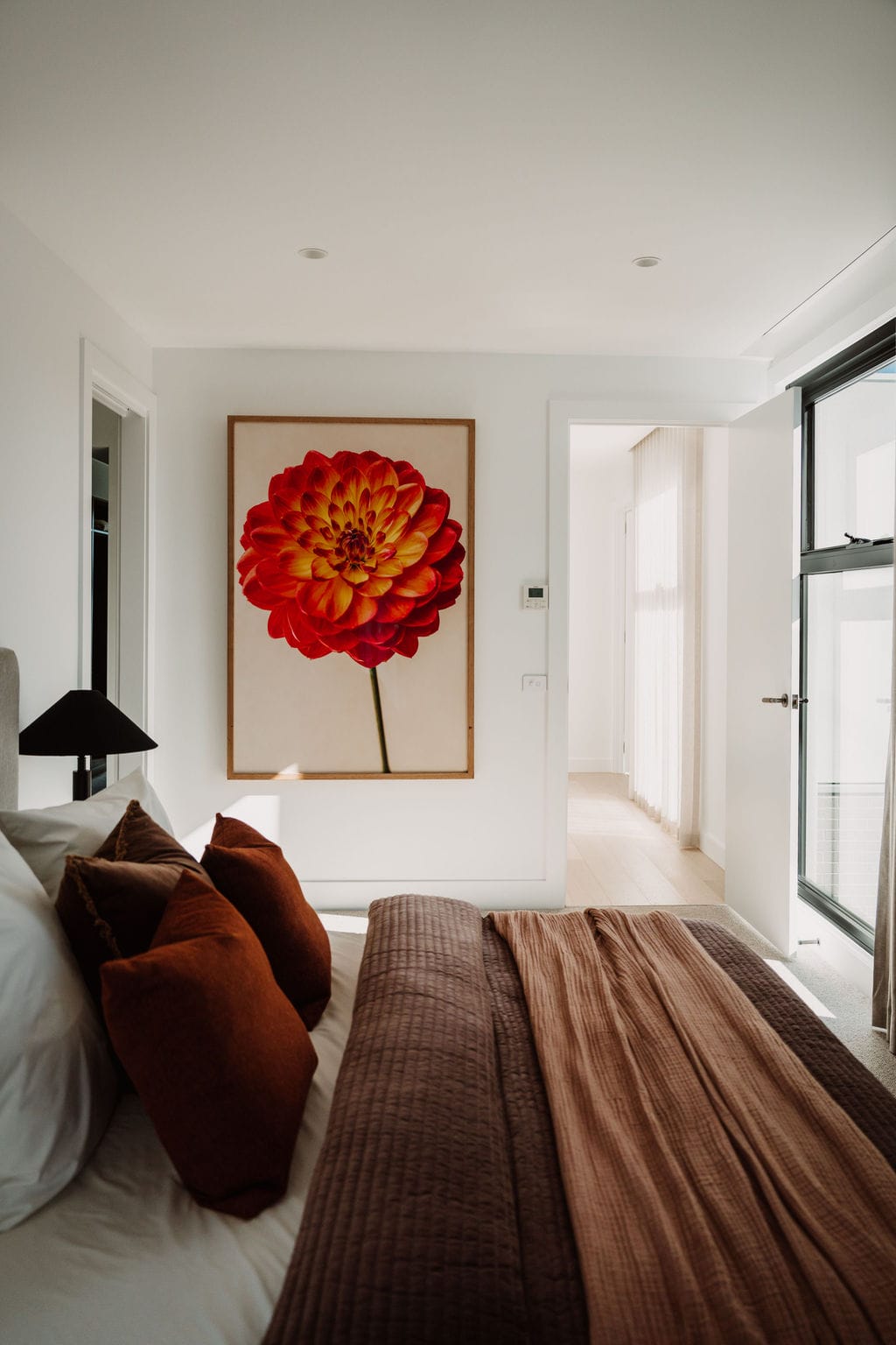 Hallway with a large red floral artwork against a pale wall, over timber flooring