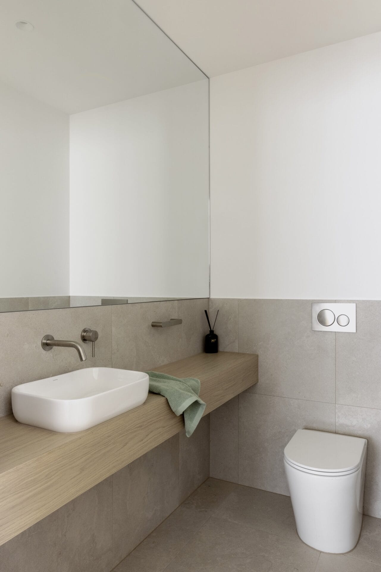 Minimal shower in soft off-white tiling with a frameless glass screen