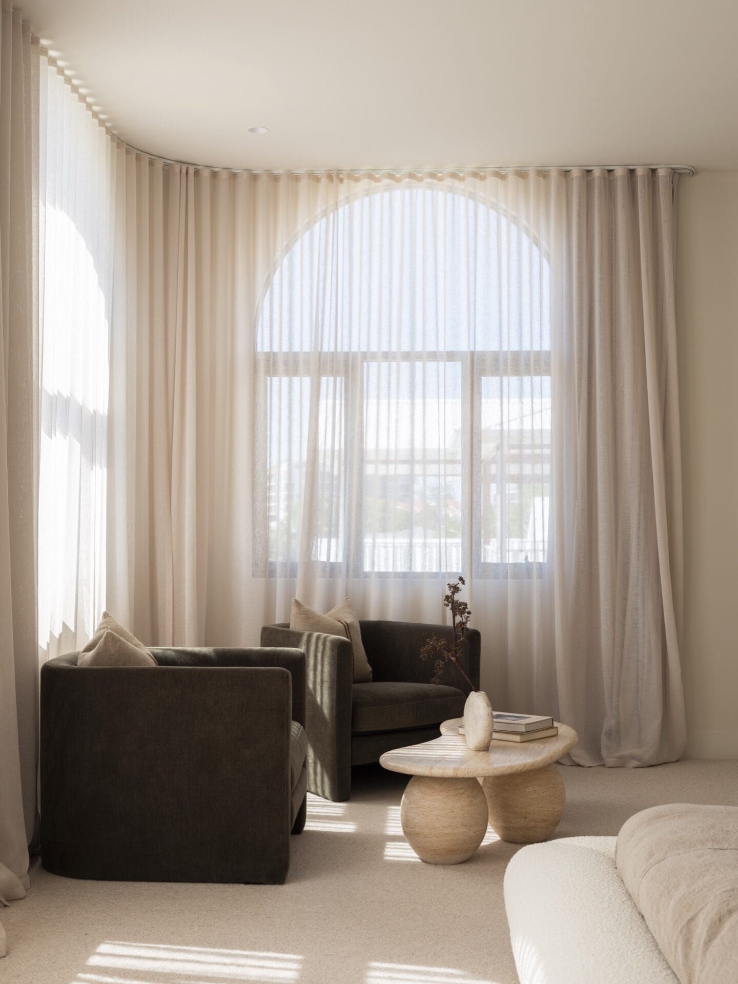 Sitting area with dark armchairs and a travertine coffee table at MARÈA