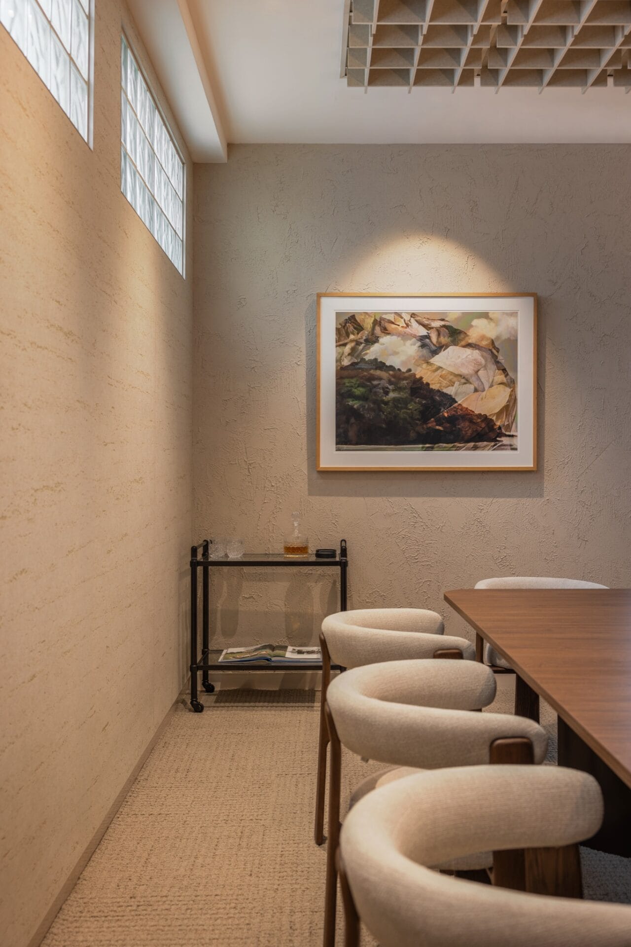 Glass block wall and framed artwork viewed from inside the boardroom, with the grid ceiling above