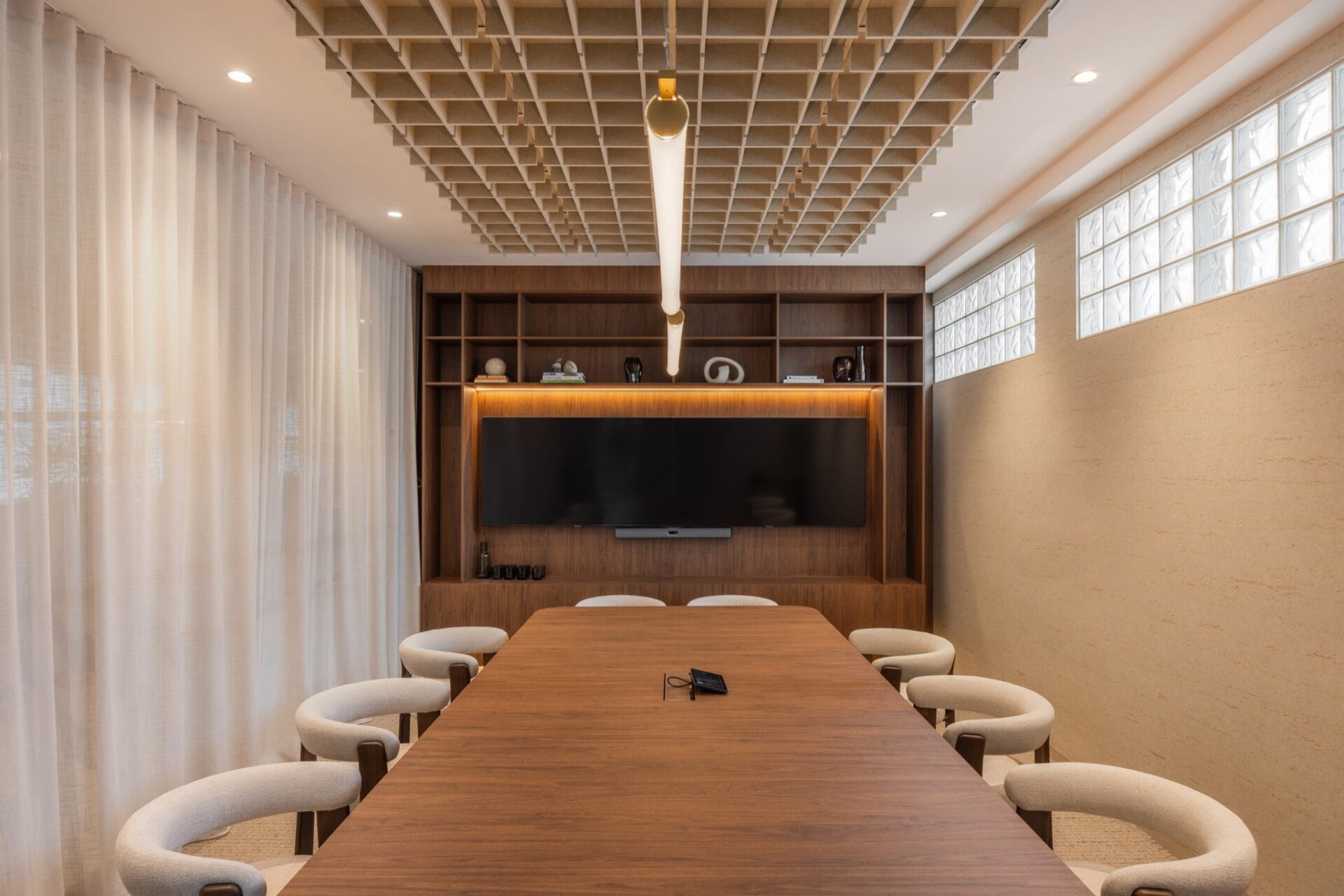 Boardroom with a long timber table, cream chairs, linear pendant and grid ceiling