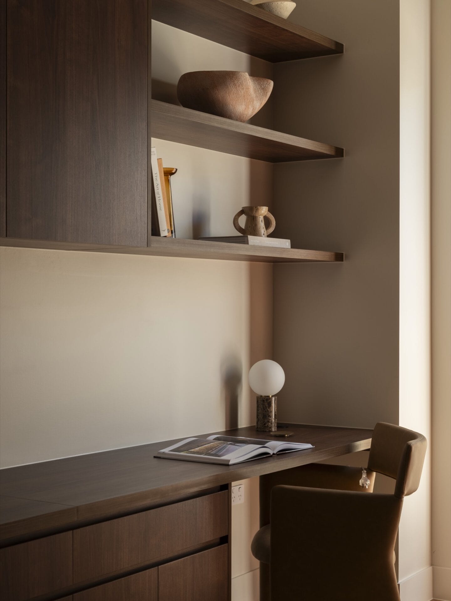 Built-in timber study nook with floating shelves and leather desk chair