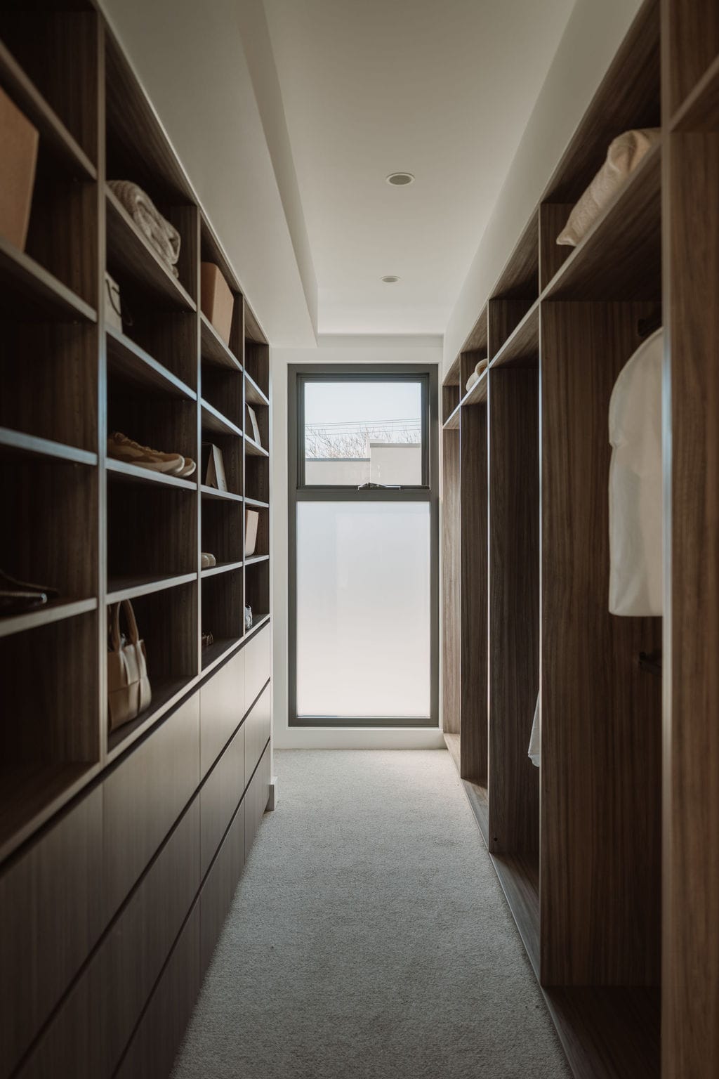Dressing room lined with timber shelving, lit by a window at the end