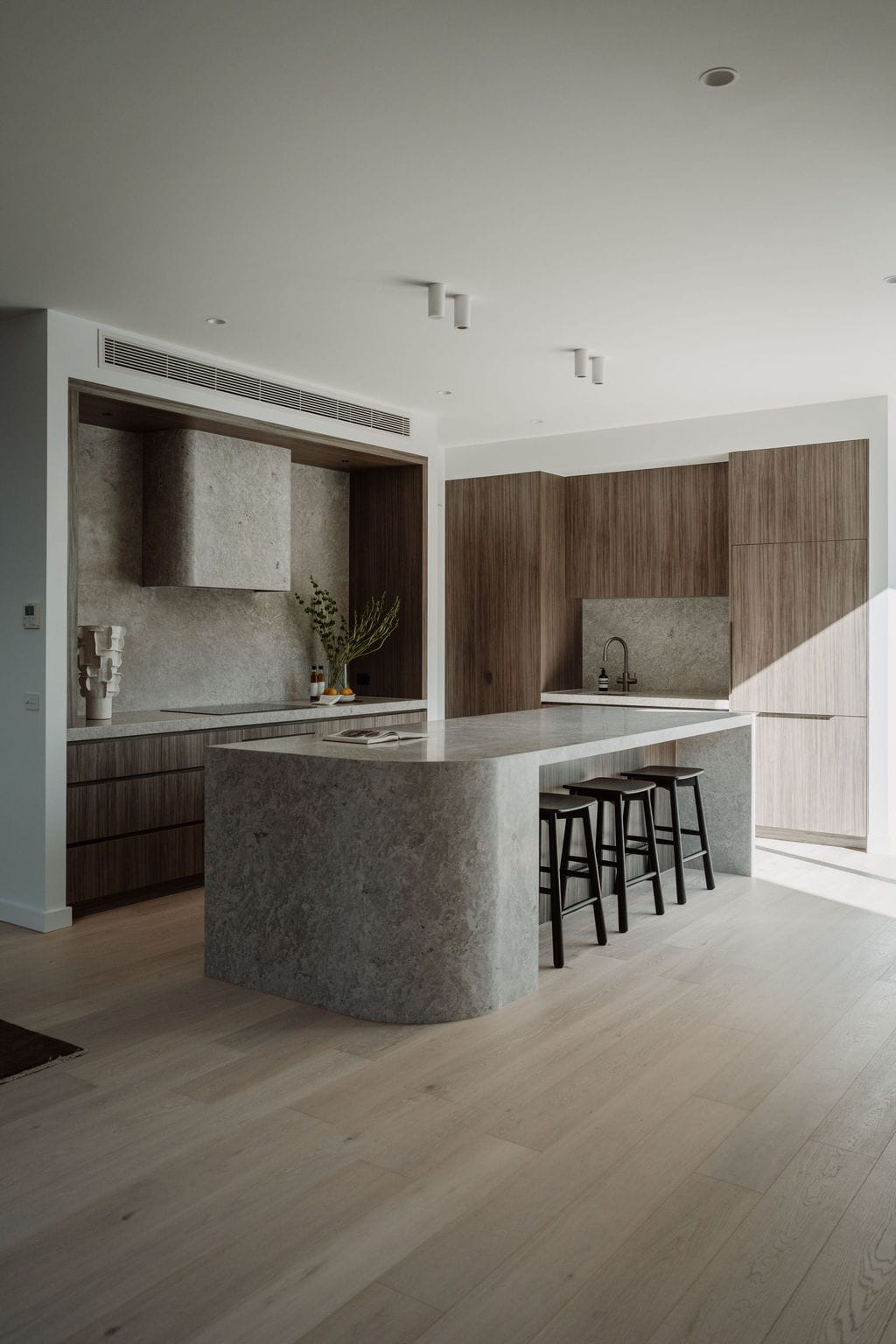 Stone kitchen island with timber stools over Alta timber flooring