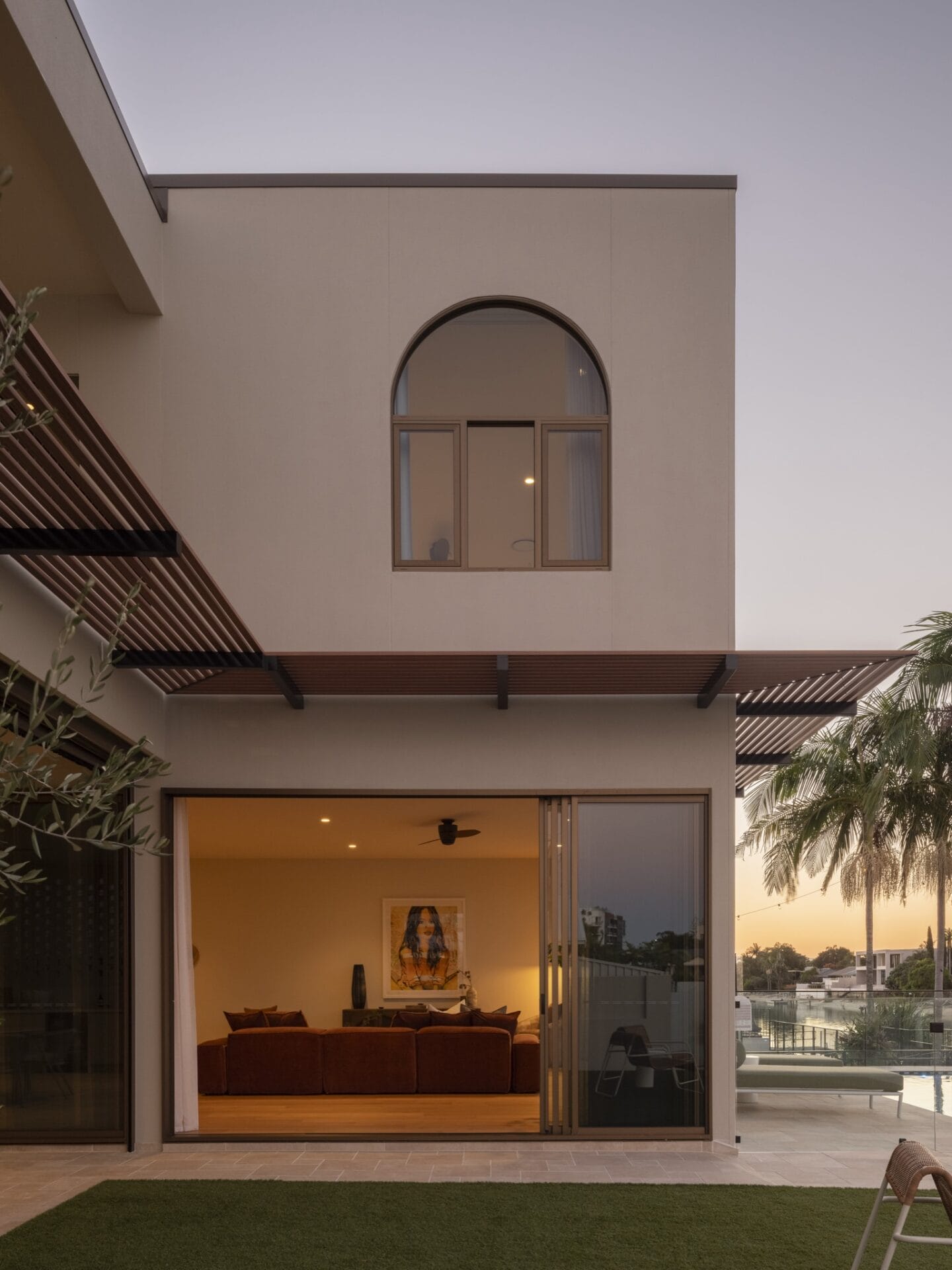 Evening view through sliding doors into MARÈA's lounge with Dakar oak flooring and rust sofa