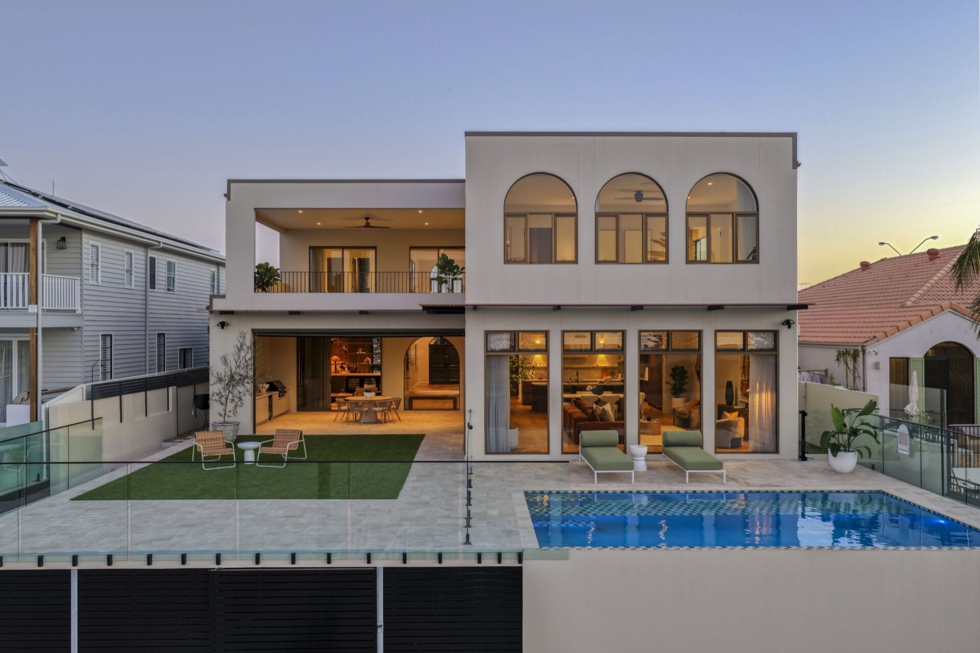 Rear of MARÈA at twilight with swimming pool and lit interiors