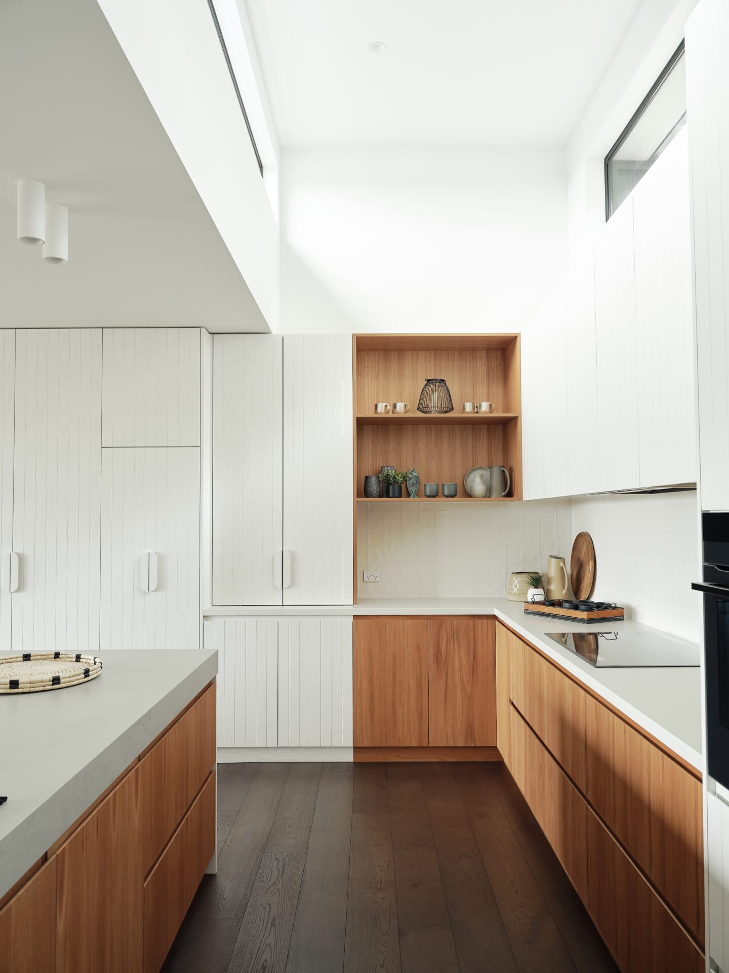 Modern kitchen with white cabinetry, a timber servery nook, and dark timber flooring flowing through to the island bench.