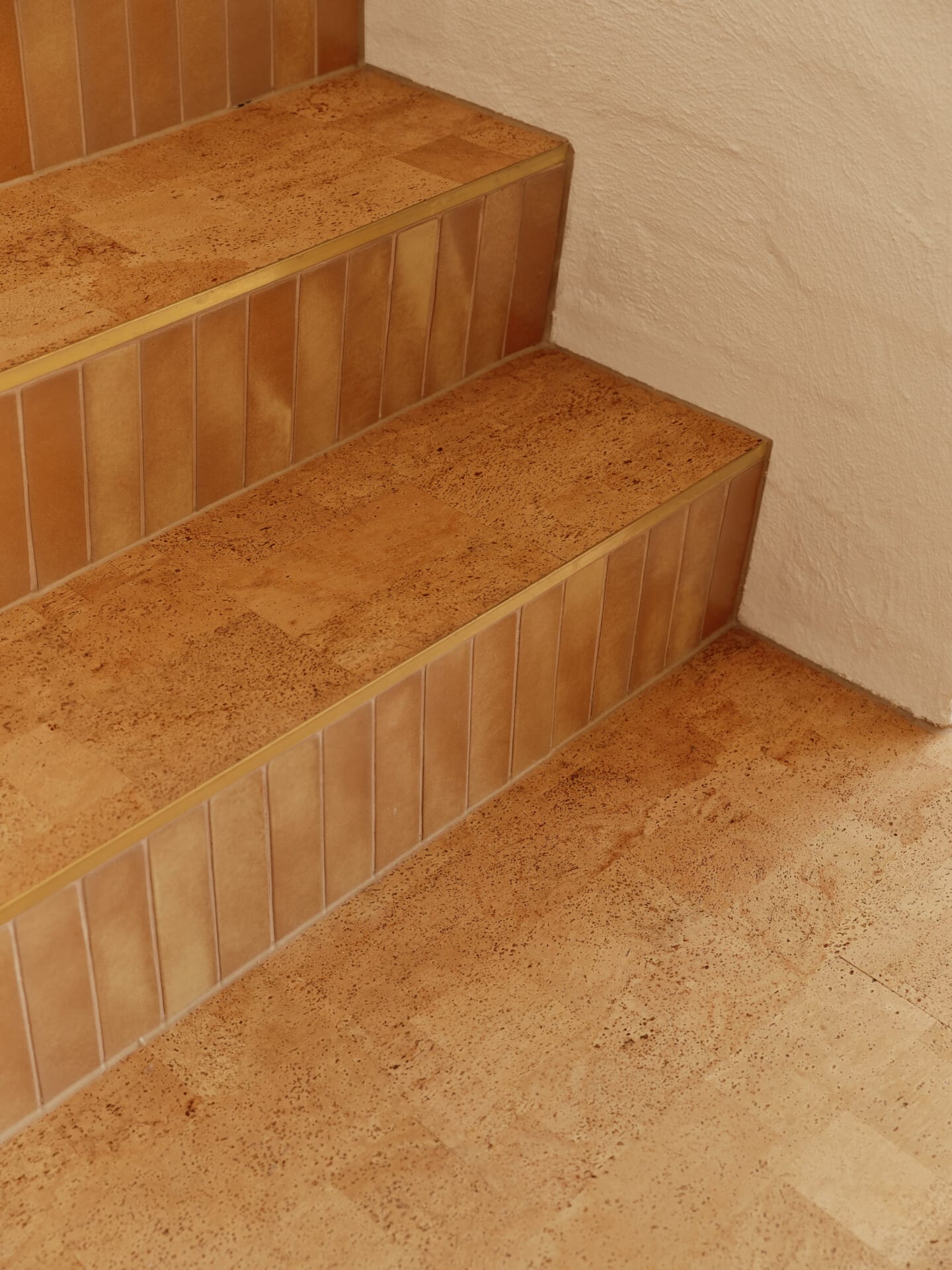 Close-up of Lisbon cork tile stairs with brass edging, leading down to the cork tile floor below.