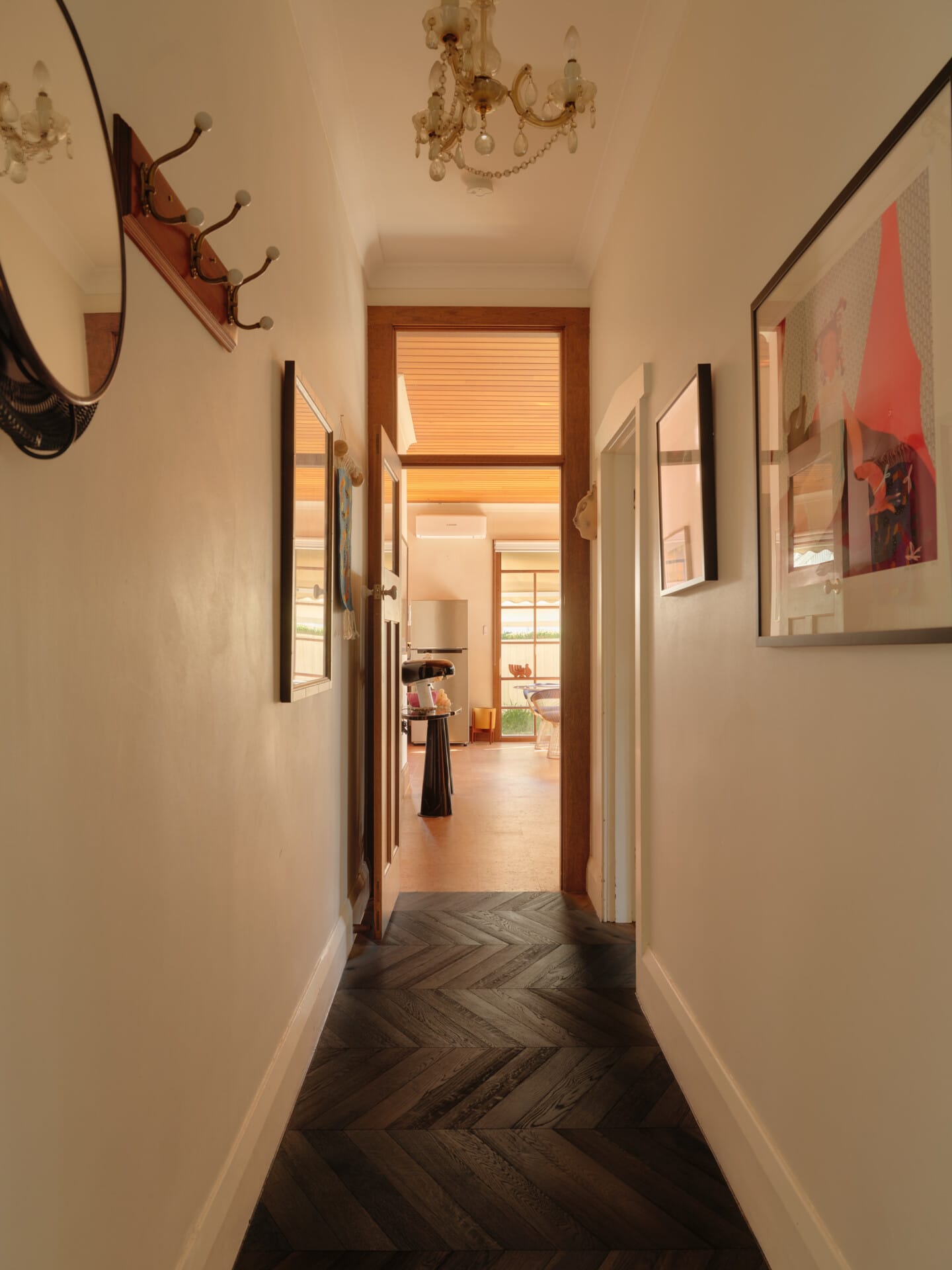 Hallway with a vintage chandelier and gallery wall, Porto cork flooring giving way to Highland Chevron timber flooring beyond.