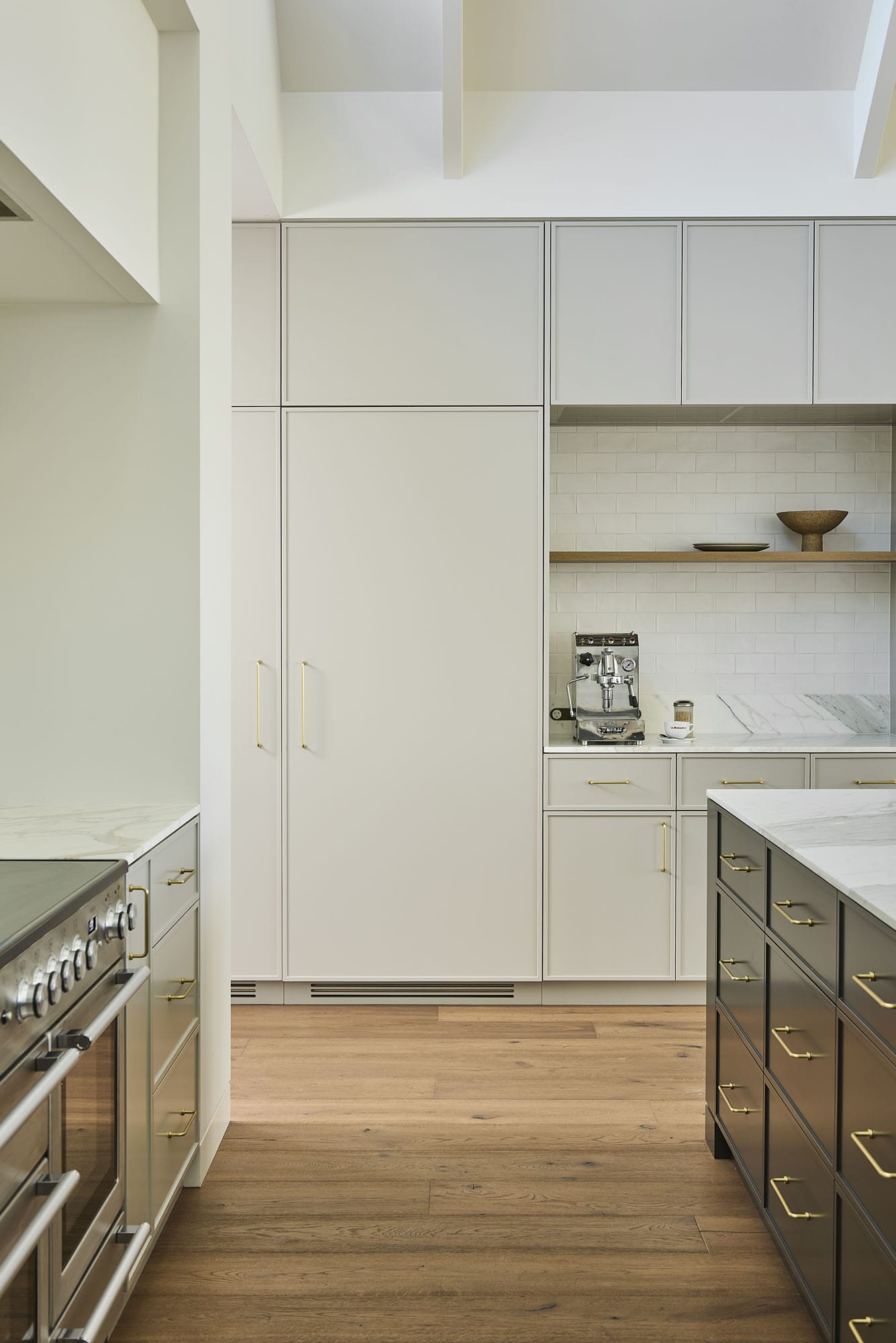 Kitchen with a freestanding range cooker, gold hardware, and Diamond Bay timber flooring leading past the servery to a dark two-tone island at Riverstone House.
