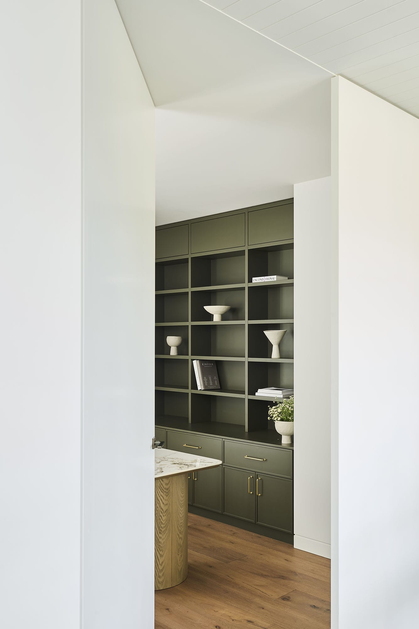 View through to a butler's pantry with olive-green joinery and open shelving, Diamond Bay timber flooring underfoot at Riverstone House.